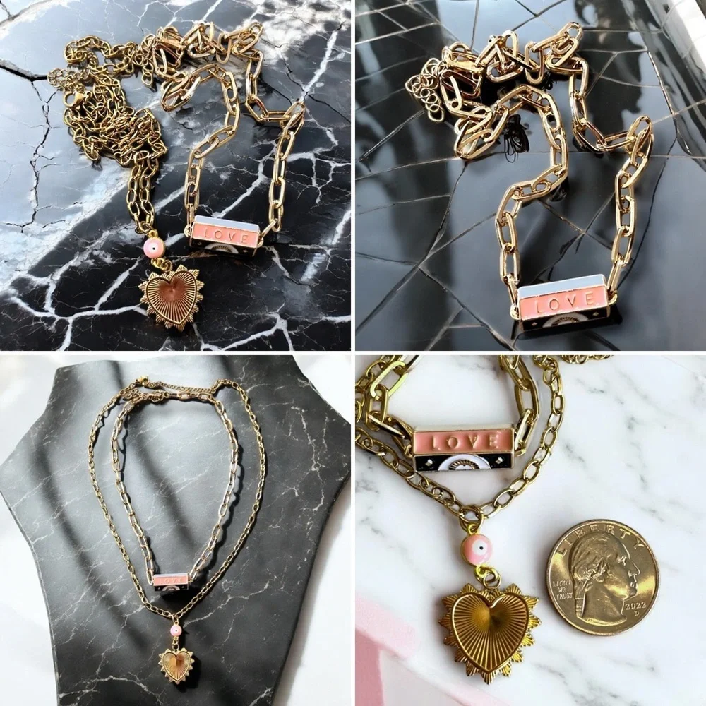 Gold toned chains with black, white, gold, and pastel pink enamel charms.